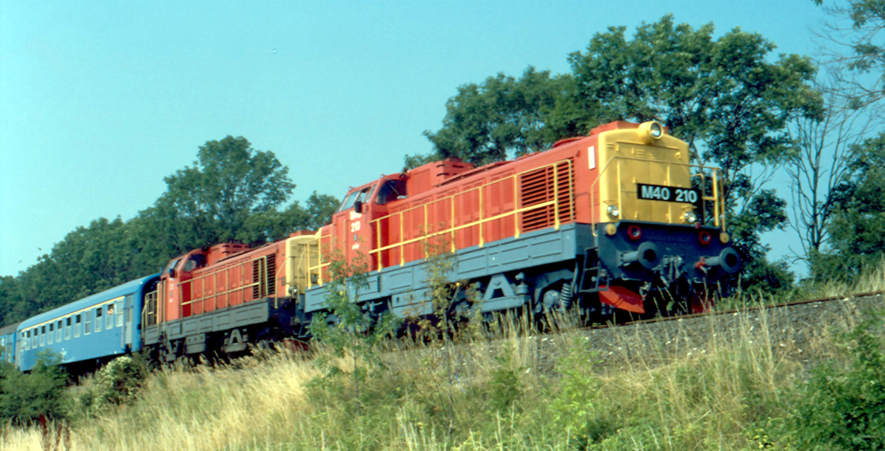 A jó időre tekintettel alighanem sok utasra számítottak Szombathelyen 1992. július 13-án. Az emiatt meglehetősen hosszúra sikeredett, Balatonfüredre közlekedő fürdővonat vontatását nem merték egy mozdonyra bízni: az M40 212 elé erősítésként a 210-es Púpost kapcsolták (fotó: Tasnádi Tamás)