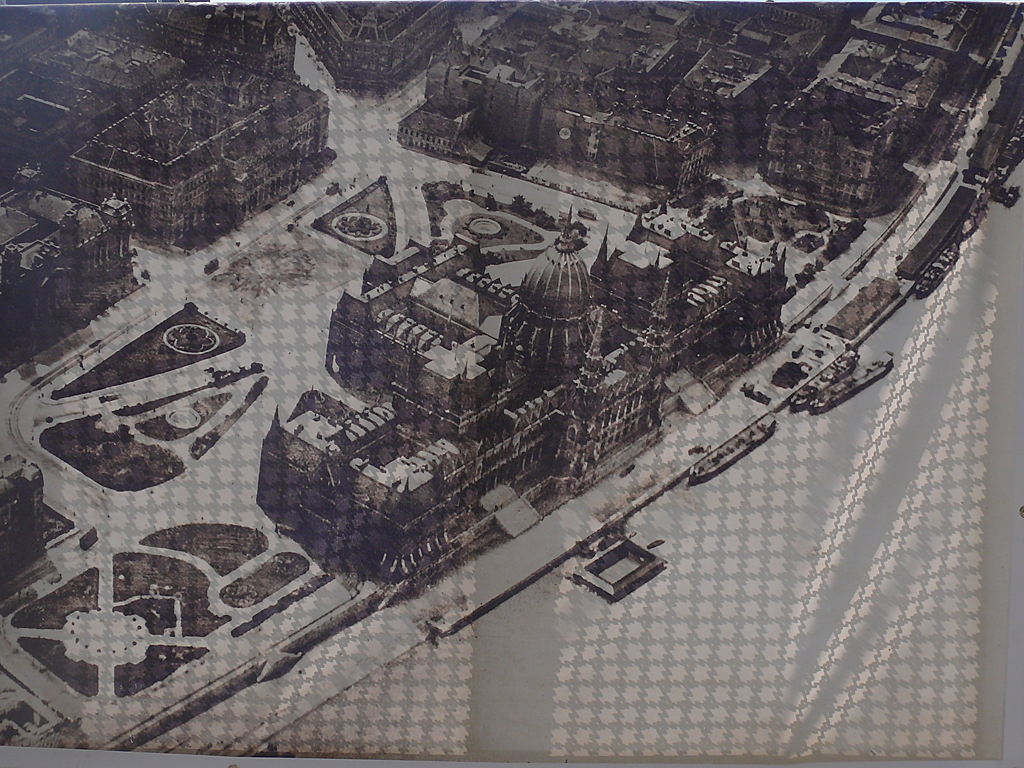 Az egyik molinó az építkezés kordonján, háború előtti légifelvétel a térről<br>A képre kattintva fotógaléria nyílik<br>(a szerző felvétele)
