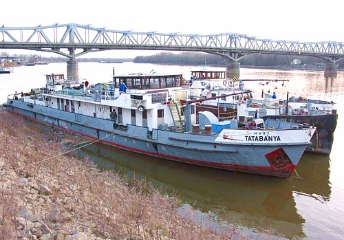 A Tatabánya motoros vontatóhajó leállítva Baján, 2004-ben. Mögötte egy uszály és a Budapestről érkezett Sopron látható<br>(fotó: Kosztolicz Péter)   
