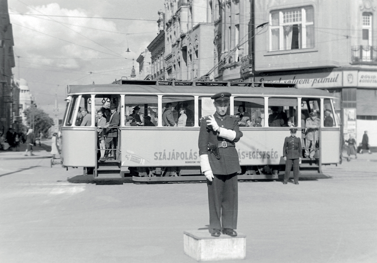 A háborús roncsból talpra állított 2, 21, 22-es kocsik valamelyike a Kossuth utcában, a távolban a Veres templom. Ezeket a villamosokat 1950–52-ben acélvázasítva állították helyre. Homlokfalukat átépítették, lekerekítették, és erősen döntött szélvédővel látták el a járműveket. Az 1967-ig közlekedő kocsik öt oldalablaka egyforma szélességű. A 21-est ekkor selejtezték, a 2, 22-esből 329+330-as számon ikerkocsit építettek (fotó: Fortepan)