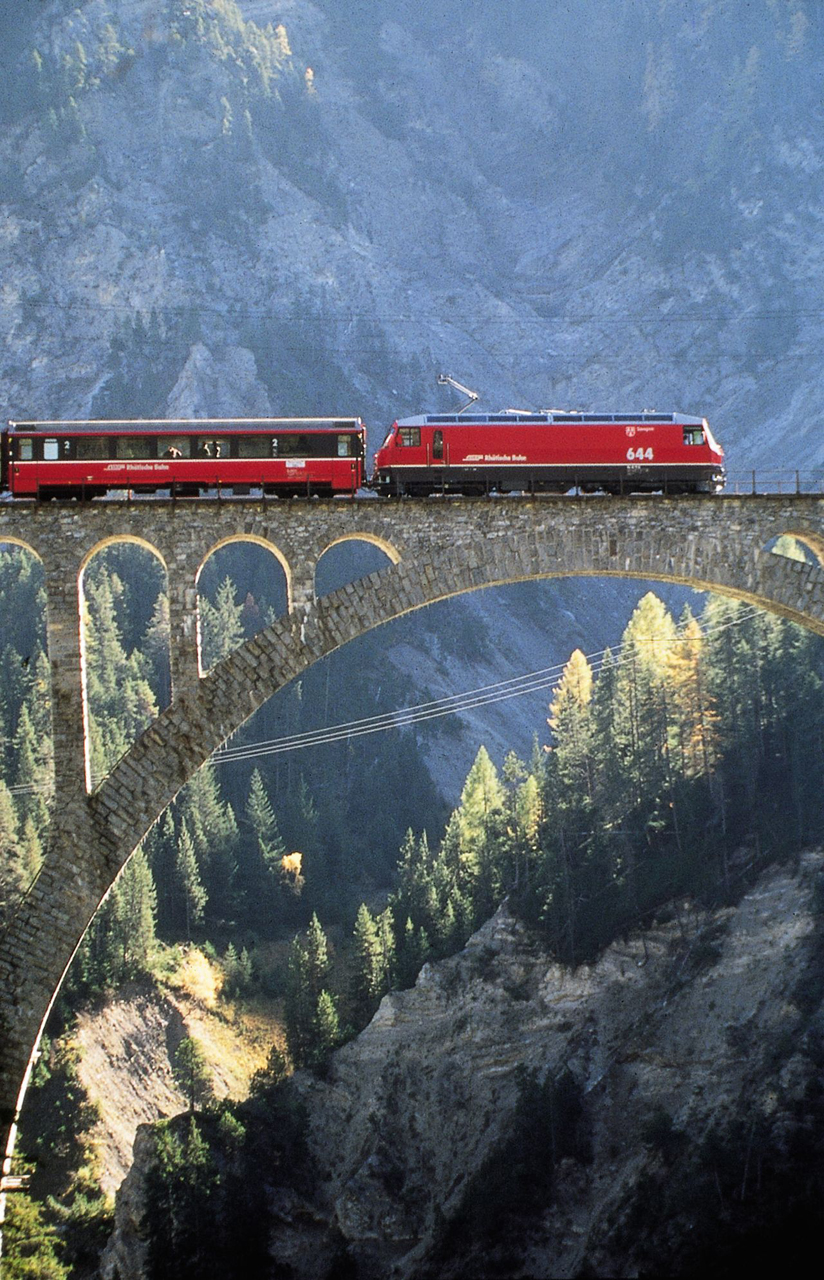 Kis vonat a hegyóriások között. Az RhB legmodernebb, Ge 4/4 III-as sorozatú mozdonyával vonatott Heidi expressz Filisur közelében, a wieseni viadukton. Ez a híd a legmagasabb az RhB hálózatán. A képre kattintva galéria nyílik (fotók: Indóház-archív | RhB)