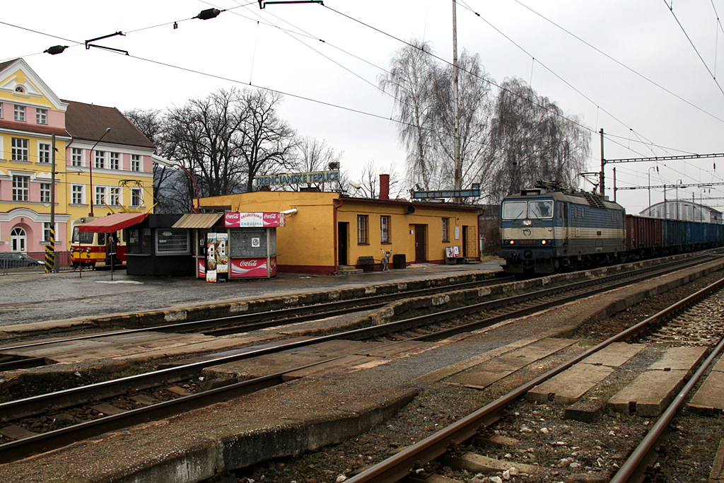 A hőlaki állomási melléképület egyik oldalán tehervonat a fővonalon, a másik oldalon kikandikál a kisvillamos<br>A képre kattintva fotógalériánk nyílik meg<br>(Tevan Imre képei 2011. február 18-án készültek)