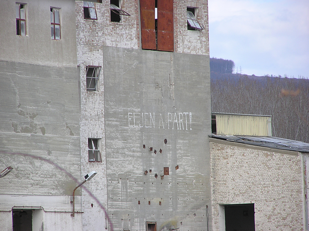 A régi őrlőmű épülete pártszlogennel. Az építményt 2012 tavaszán robbantással semmisítették meg, a telep vágányhálózatát szintén ekkor szedték fel
