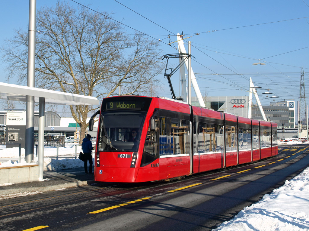 <p>Több mint egy negyedszázaddal később, de az előző kép helyszínétől alig néhány méterre a Bernmobil 671-es pályaszámú, a svájci típusjelölés szerint Be 6/8 jellegű Combino villamosa érkezik Wankdorfplatz megállóhelyre, 2012. december 12-én</p>