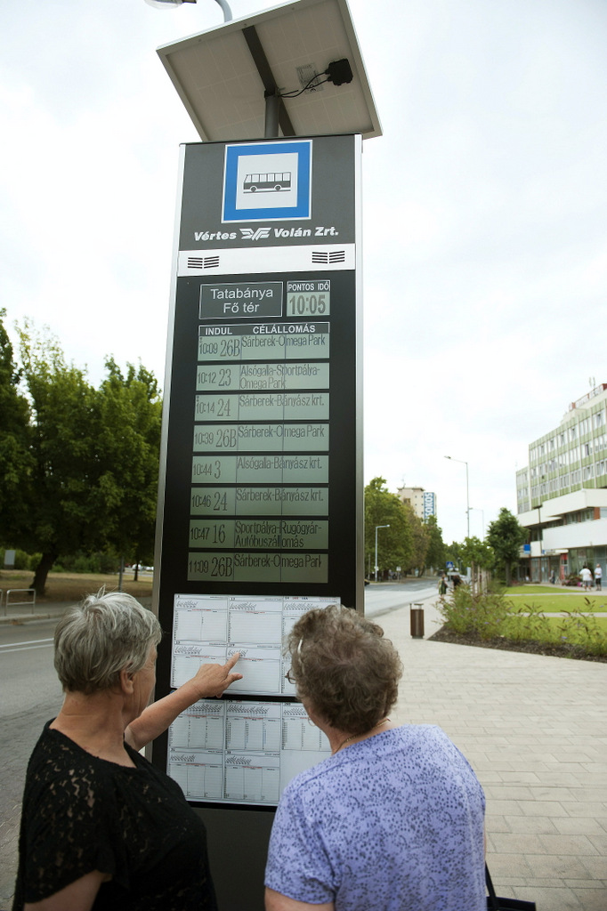 Utasok nézik a Vértes Volán megújult elektronikus forgalomirányítási és utastájékoztató-rendszerének egyik utastájékoztató-oszlopát Tatabányán egy buszmegállóban<br>(fotó: MTI / Koszticsák Szilárd)