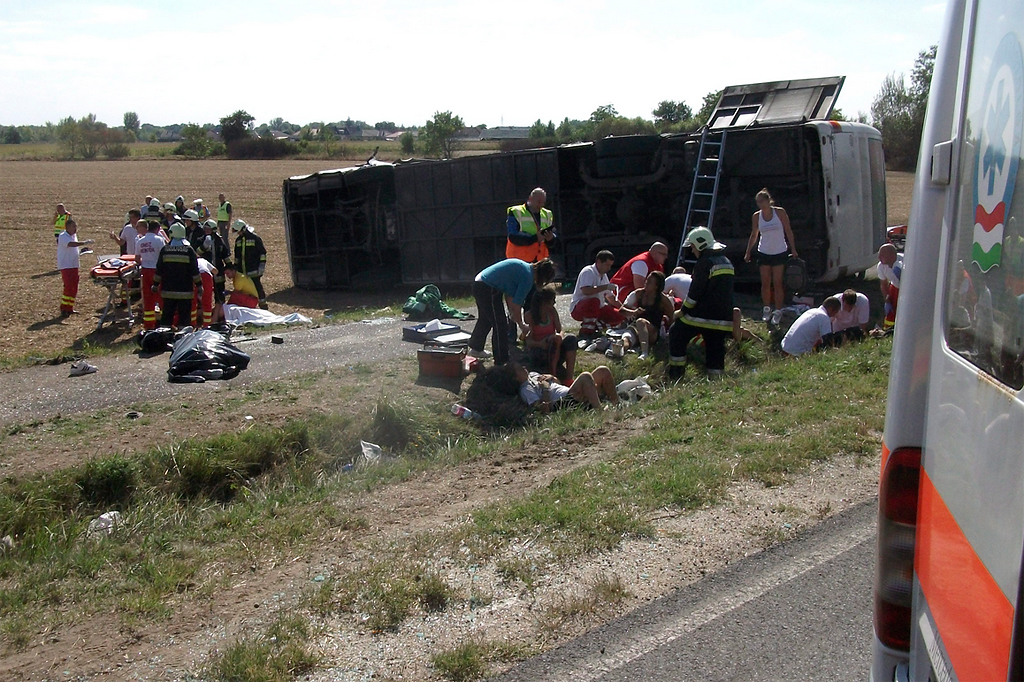 A mentők látják el a baleset sérültjeit az oldalára borult, összeroncsolódott autóbusz mellett