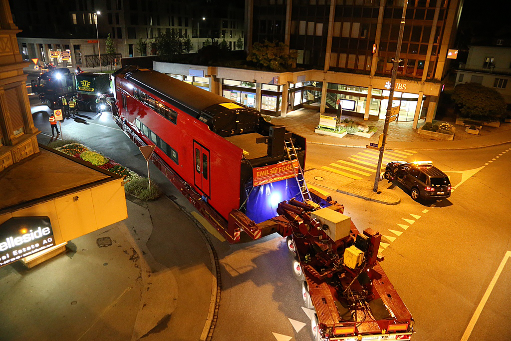 Tekereg a járműszerelvény a szűk városi utcákon, cél: a bázeli kikötő<br>A képre kattintva galéria nyílik<br>(a képek forrása: Stadler Trains Magyarország Kft.)