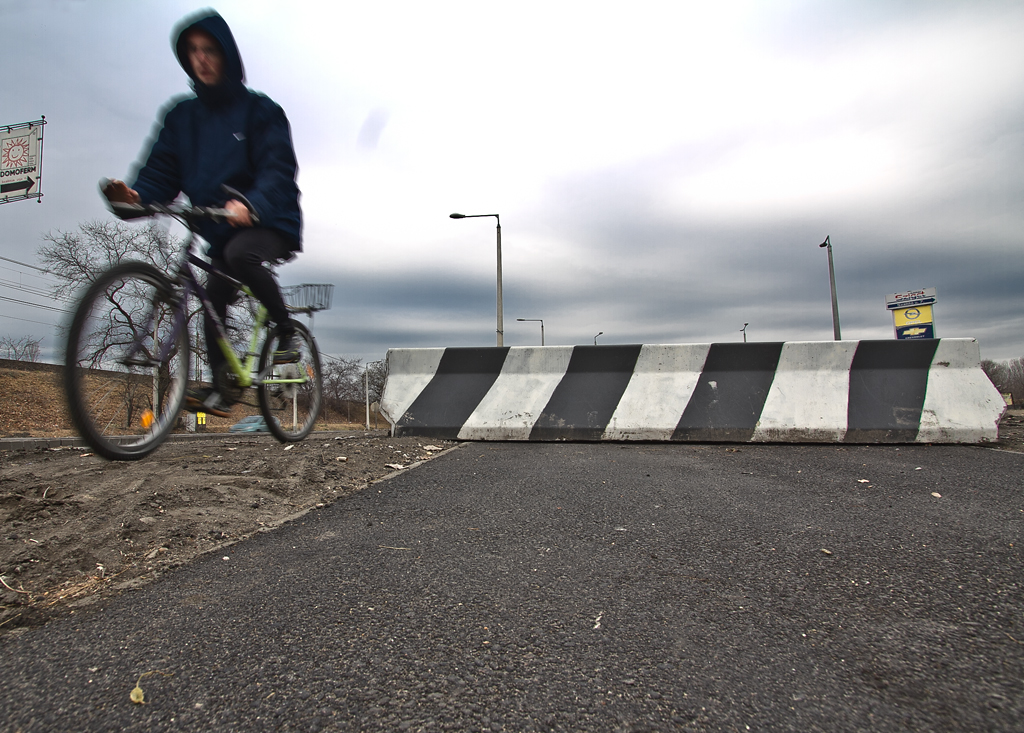Kerékpáros kóvályog a betontömbök közt – még így is jobb, mint a Weiss Manfréd úton a kamionok között<br>A képre kattintva galéria nyílik<br>(videó és fotó: Vörös Attila)