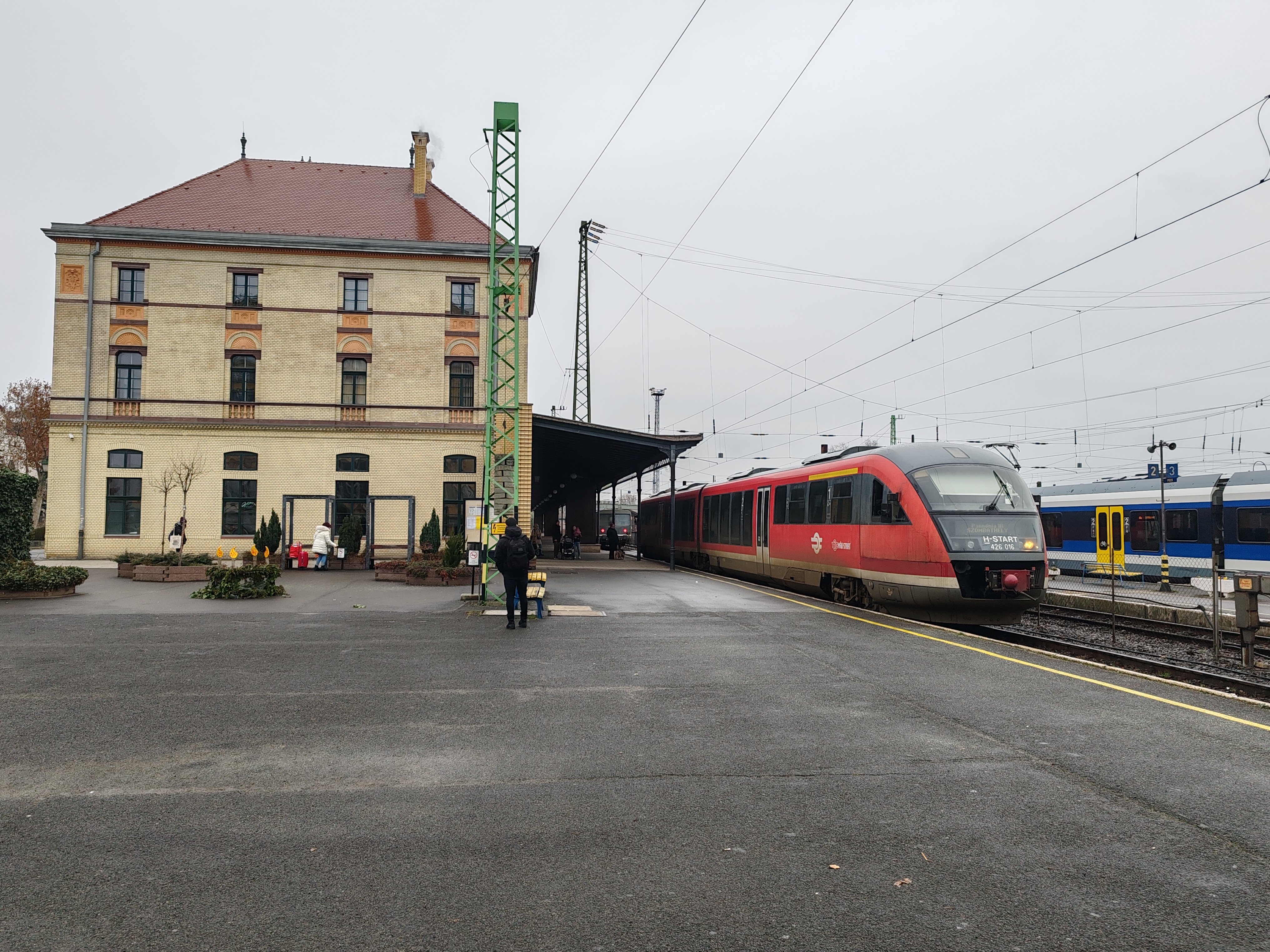 Egy ilyen kép ma, az év utolsó napján, december 31-én nem készülhetett volna, mivel a Pécsről 12:13-kor Szombathelyre induló Pannónia IR (8995) csak Szentlőrinctől közlekedett. Huszonnegyedikén azonban a 016-os Dezső rendben, a megszokott helyéről indult Szombathelyre. Menesztés előtt háromfős Ghostbusters kommandó takarította ki a kocsit, egyikük hátára felcsatolva a Reitman-filmben megismert protonágyúkhoz hasonló porszívó fejtette ki a kívánt hatást. A húsz éve MÁV állományba vett elővárosi ikermotorkocsin már látszik a kor, menet közben a Jacobs-futóforgóváz fölött ülve folyamatos a szuflé (meg másnak is) a zsinatolása, nyikorgása, de a 800 lóerő körüli összetett névleges motorteljesítmény látszólag megvan, ahol csak lehetett, bátran haladt a 016-os