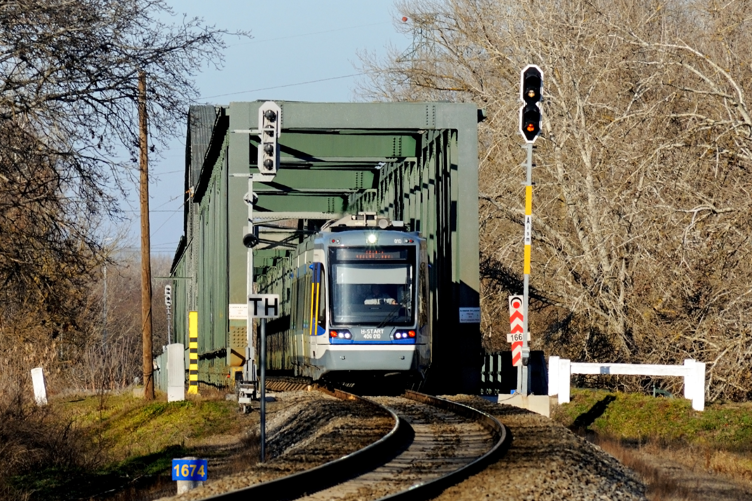 Sárgulás előtt a flotta. 33061-es TramTrain halad az Algyői vasúti Tisza hídon (fotó: Harmati Marcell)