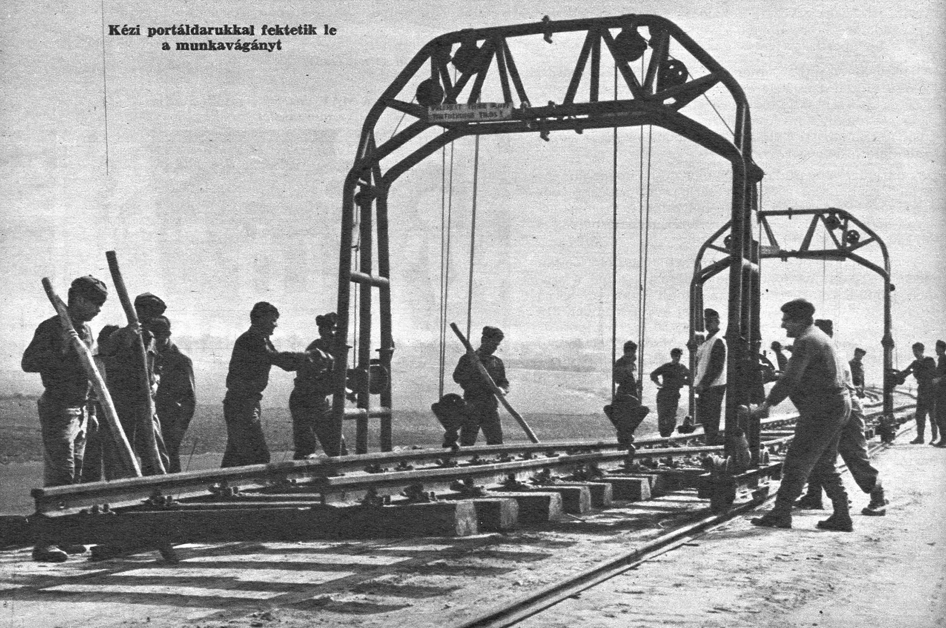 Pályaépítés. A néphadsereg sorköteles katonái a MÁV szakembereinek vezényletével, kézi portáldarukkal fektetik le a munkavágányt