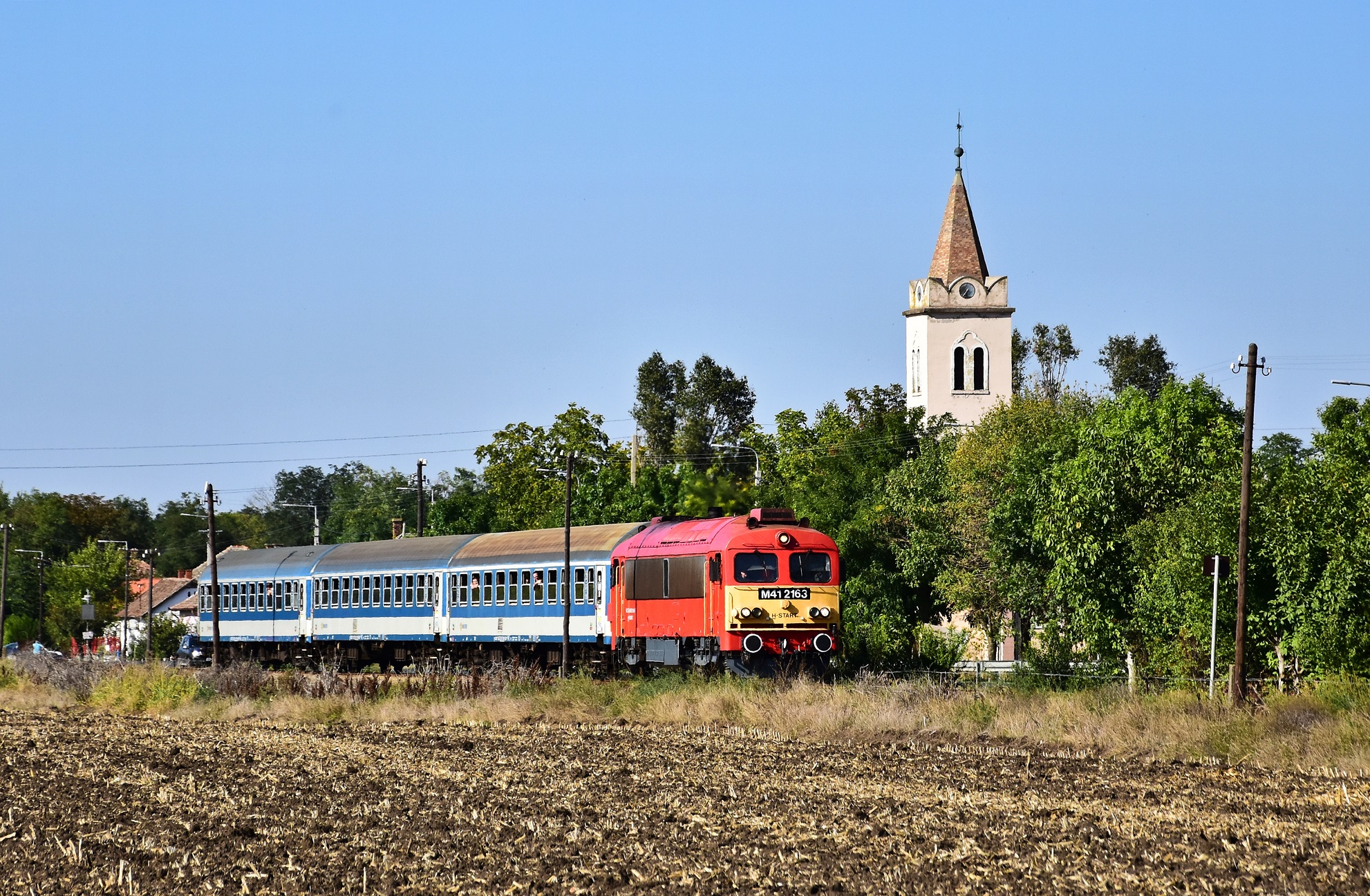 A Mezőtúr–Mezőhegyes viszonylatú 37314-es számú személyvonat csattog az 1938-ra felépített Kardoskúti Evangélikus templom mellett. Érdekesség, hogy ez az első tanyai evangélikus istenháza hazánkban