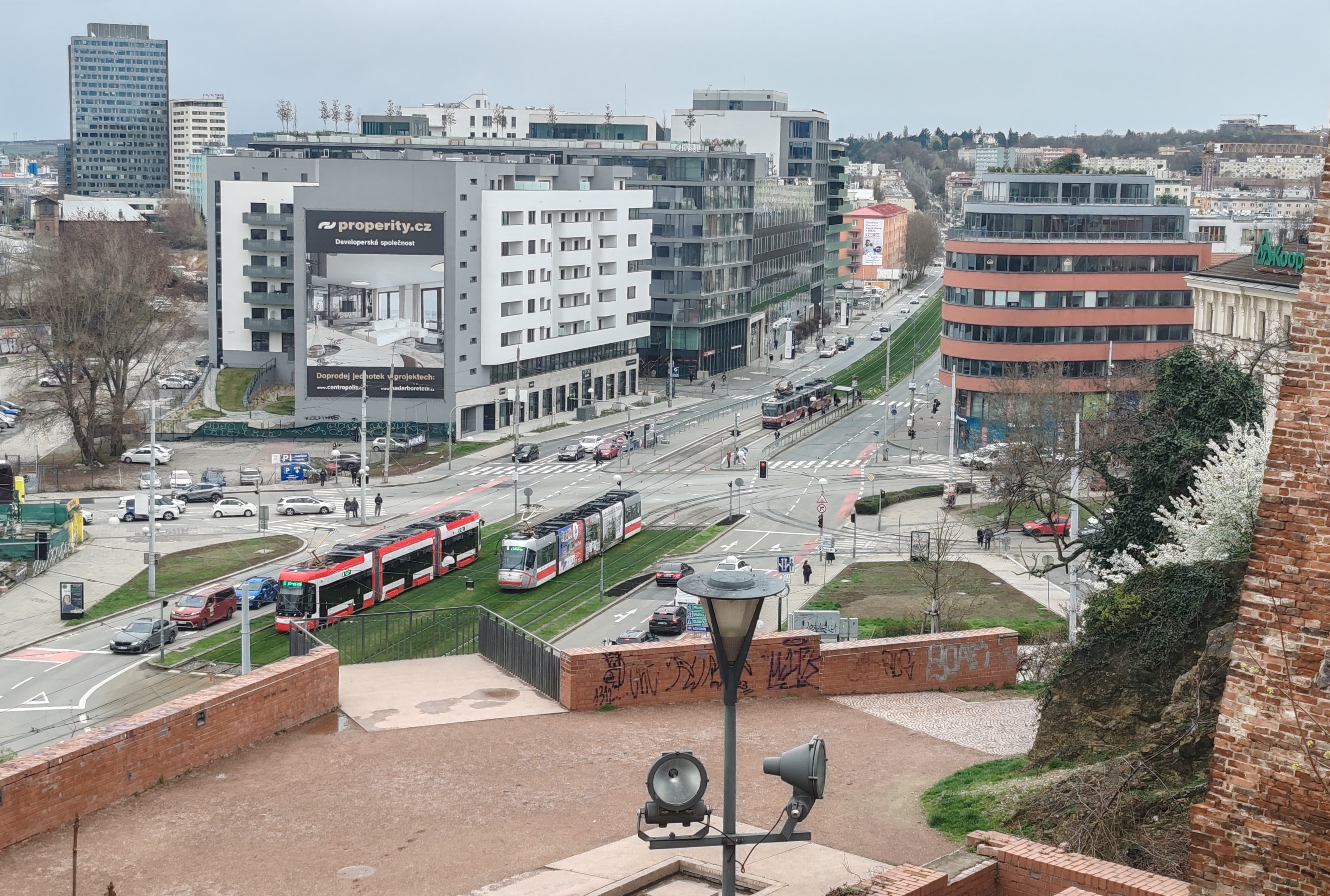 Rálátás a pályaudvar közelében Špilberk vára mellvédjéről. Három villamos, három típus: a háttérben, a megállóban egy Tatra KT8D5, jobbról Škoda 13T érkezik, balra, szintén a füves pályán pedig a 1760–1764 pályaszám tartományba sorolt öt Škoda45T egyike (fotó: T. H. F.)